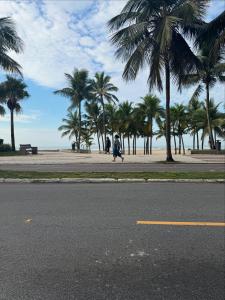 a person walking down a street with palm trees on the beach at Apartamento Fb in Água Boa