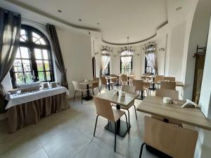 a dining room with tables and chairs and windows at Villa Stary Kalisz in Kalisz
