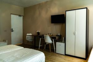 a bedroom with a bed and a desk with a television at Hotel De Elderschans in Aardenburg