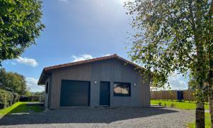 a garage with a blue door and a tree at Gîte des Peupliers in Courlay