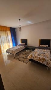 a bedroom with two beds and a rug at Résidence les Fatimides in El Aouina Station