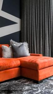 eine orangefarbene Couch in einem Zimmer mit einem Vorhang in der Unterkunft Квартира с видом на парк,в минуте ходьбы от Акимата,Налоговой, Прокуратуры,Рахмета,Dostyk Mall,ЦОНа in Petropawlowsk