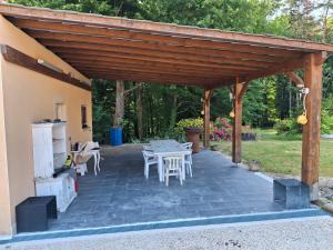 a wooden pergola with a table and chairs on a patio at Le Repaire de Belette in Coulounieix-Chamiers