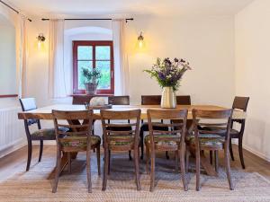 a dining room table with chairs and a vase of flowers at Chalupa mezi stezkami in Hejnice
