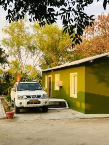 a white truck parked in front of a yellow and green house at Ehalo Ndjoko which means small beginnings in Ondangwa
