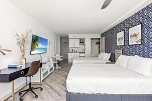 Una habitación de hotel con dos camas, un escritorio y una cocina. en Ocean View Suites at Oceanside Inn, en Daytona Beach