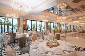 uma sala de jantar com mesas e cadeiras brancas e lustres em Amadria Park Hotel Royal em Opatija