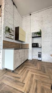 a kitchen with wooden floors and a white brick wall at Квартира-студія в історичному центрі міста біля Центральної площі in Chernivtsi +16 photos