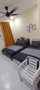 two beds in a room with a ceiling fan at Roomstay Cheq Ayoh Pantai Penarik Setiu in Kampong Ru Sepuloh +10 photos