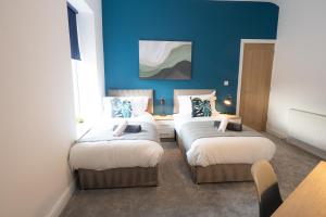 two beds in a room with blue walls at Modern House Ideal For Families and Contrators in Padiham