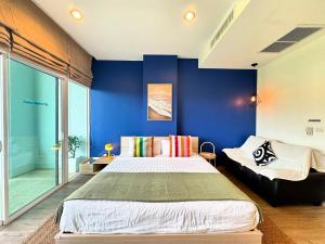 a bedroom with a large bed and a blue wall at Veloche Peaceful Condo In Karon Beach in Ban Karon +17 photos