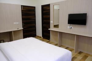 a bedroom with a bed and a flat screen tv at Hotel Ram Janki Inn Ayodhya in Ayodhya