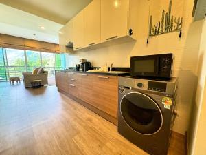 a kitchen with a washing machine and a microwave at Veloche Peaceful Condo In Karon Beach in Ban Karon