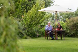 um homem e uma mulher mais velhos sentados numa mesa debaixo de um guarda-chuva em Cnapan Guest House em Newport