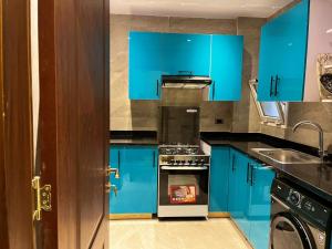 eine blaue Küche mit Herd und Spüle in der Unterkunft Diva 2BDR , Madinaty in Madinaty + 17 Fotos