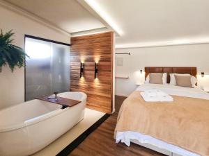 ein Schlafzimmer mit großem Bett und Badewanne in der Unterkunft Monte Paraíso - banheira e vista da Pedra Menina in Espera Feliz