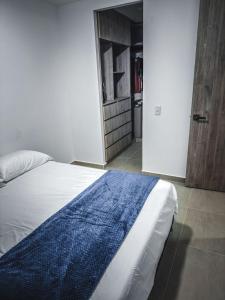 a bedroom with a bed with a blue blanket on it at Moderno apartamento cerca de las mejores clínicas de la ciudad in Floridablanca +13 photos