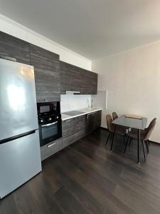 Una cocina con refrigerador y una mesa con sillas. en Panorama Dnipro apartment, en Dobrovelychkivka