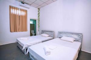 twee bedden in een kamer met witte muren en een raam bij Villa Eva in Matara