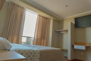a hotel room with a bed and a large window at Hospedaje Andina H&M in Tacna
