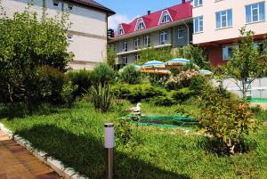 a garden with a bird in the grass next to buildings at Edelveis Guest House in Lazarevskoye