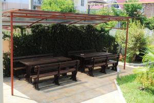 two picnic tables and benches under a pergola at Edelveis Guest House in Lazarevskoye