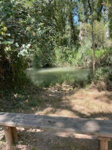a wooden bench sitting in front of a river at El Rincón del Agua in Mogón