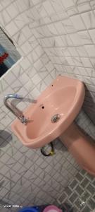 a pink sink in a white tiled bathroom at Jongki khun stay inn in Mawlynnong