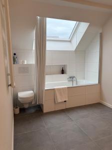 a bathroom with a tub and a toilet and a window at The Gallery Saint-Gilles in Brussels