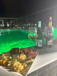 a plate of food and wine next to a swimming pool at Refúgio no Bessa in João Pessoa