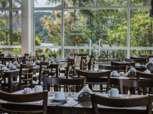 a restaurant with tables and chairs and a large window at Loft 5 Andar in Mangaratiba