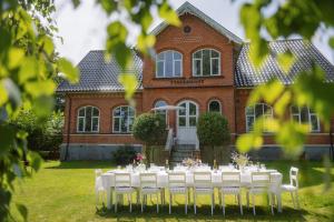 a table with white chairs in front of a house at Romantic farmhouse with wonderful garden in Ærøskøbing