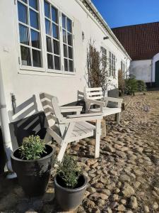 two chairs and a bench in front of a building at Mini-lejlighed med køkken - deler bad og toilet med nabolejlighed 1 in Asperup