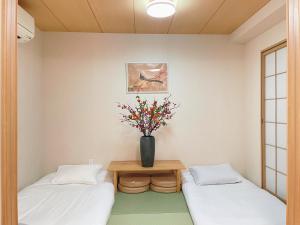 a room with two beds and a vase with flowers at Home Stroy in Tokyo-VENTI Okachimachi 東京屋語 in Tokyo