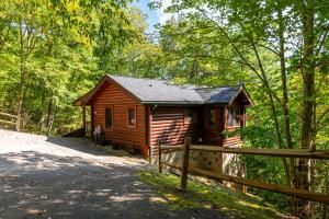 una cabina nel bosco accanto a una recinzione di Briar Brook - Private Smoky Mountain Luxury Log Home with 2 Fireplaces, Hot Tub & Community Pool a Sevierville