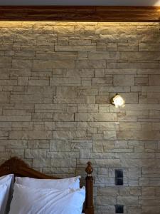 a brick wall behind a bed in a bedroom at MetsoVillas στο κέντρο του Μετσόβου in Metsovo