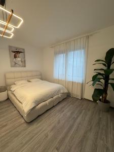a bedroom with a white bed and a potted plant at Alia Residence in Buzau
