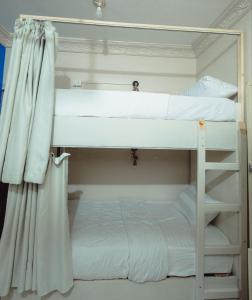 アスワンにあるPajama Hostelのカーテン付きのドミトリールームの二段ベッド2台分です。