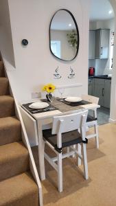 einen weißen Esstisch mit einem Spiegel an der Wand in der Unterkunft Cosy 1 bedroom apartment near Woodstock and Oxford in Kidlington
