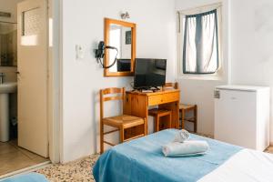 a room with a bed and a desk and a television at Dilino in Kamari