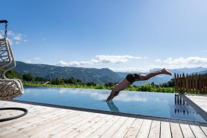 un hombre haciendo un salto en una piscina en Apartments Schmalzerhof - Eppan an der Weinstraße, en Appiano sulla Strada del Vino
