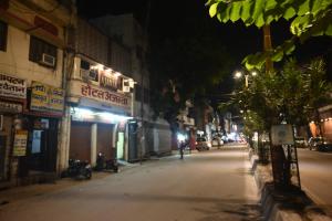 a city street at night with people sitting on the sidewalk at Hotel Ajanta Rekabganj Faizabad Ayodhya in Jāmb