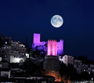 a full moon rising over a castle with a city at Domus Aura in Itri