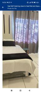 a bedroom with a white bed with a purple curtain at Vacation Home in Vanderbijlpark