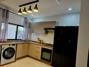 a kitchen with a black refrigerator and a dishwasher at Zachi Zebra Apartment in Kitwe