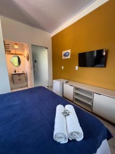 a bedroom with two towels on a bed with a tv at Suítes Preguiça in Sao Jorge