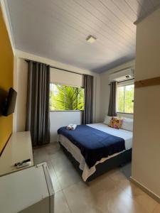 a bedroom with a bed and two windows at Suítes Preguiça in Sao Jorge