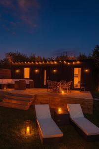 a wooden deck with a table and chairs at night at Lakefront cabin on Skåne's largest island in Ivö