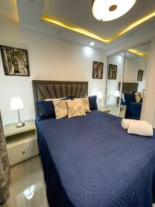 ラ・ロマーナにあるEncanto Luxury Stay - Romana del Oesteのベッドルーム1室(青い掛け布団、鏡付)