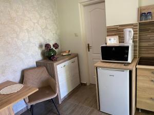 eine Küche mit einem Kühlschrank und einem Tisch mit einer Mikrowelle in der Unterkunft Sára Vendégház in Hajdúböszörmény
